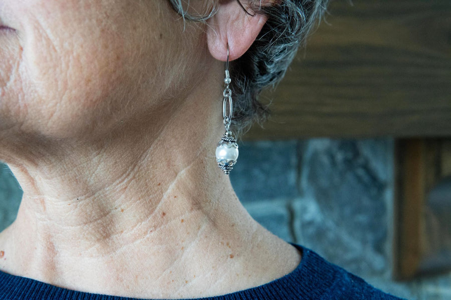 Ornate white pearl earrings on woman