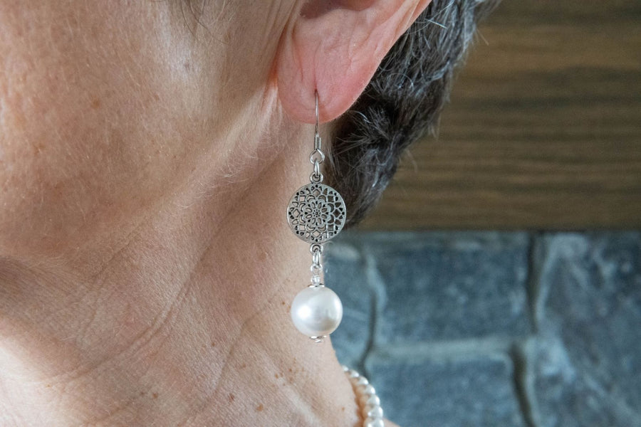 Antique silver and white pearl earrings on woman's ear