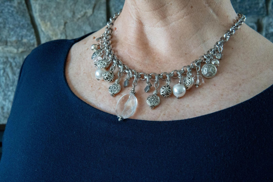 Silver, stainless steel and pearl charm necklace on woman's neck