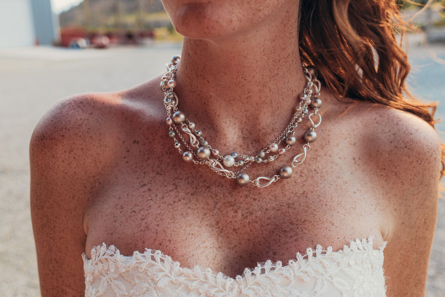 A woman in a wedding dress wearing a Carolily Finery statement necklace made of sterling silver, European crystal pearls, freshwater pearls and European crystal
