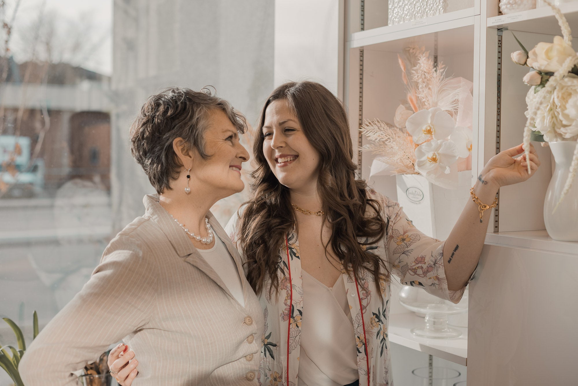 Mother and daughter wearing statement jewelry, smiling at each other