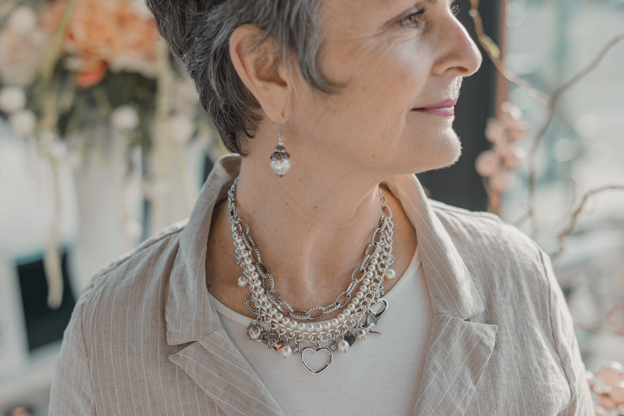 Woman wearing a silver, pearl and charm statement necklace