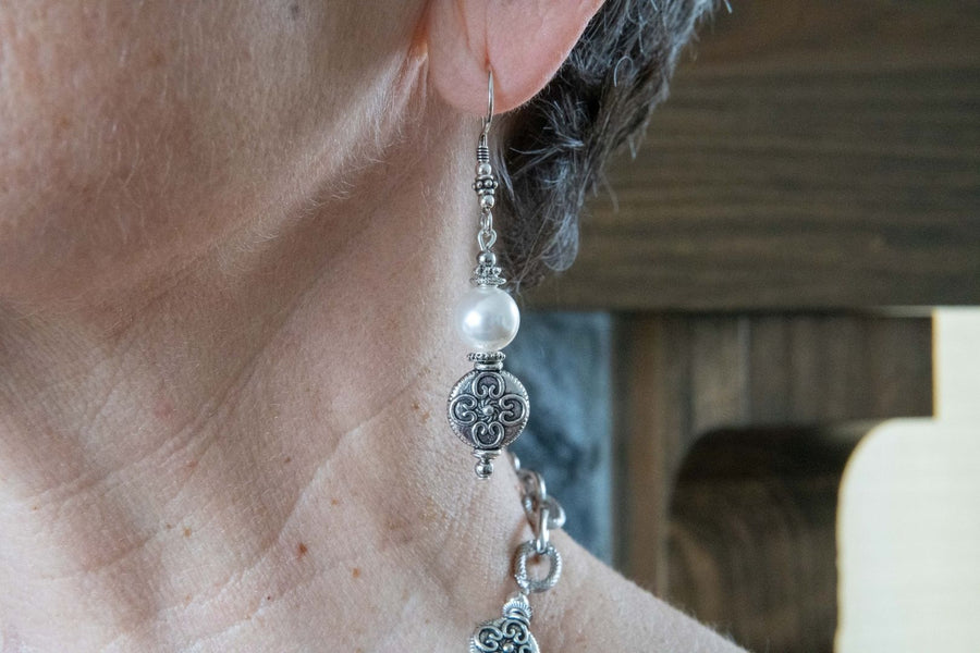 White pearl drop earrings on woman's ear