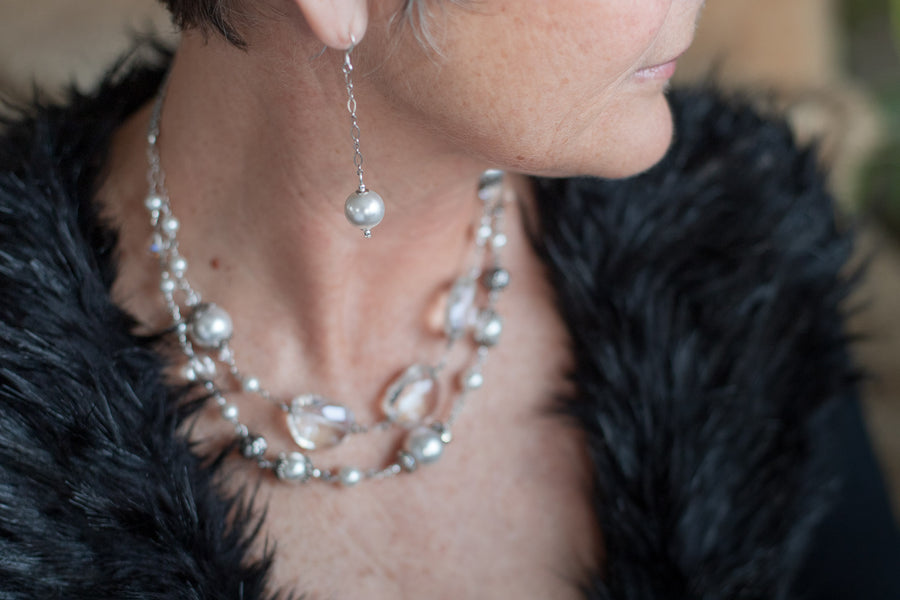 A close up of a woman wearing a Carolily Finery earrings made of sterling silver chain and one hanging European  crystal pearl