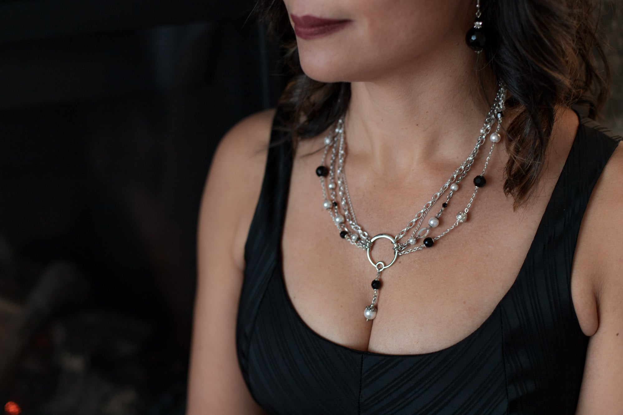 A woman in a black top wearing a Carolily Finery statement necklace made from sterling silver, onyx and European crystal pearls