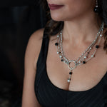 A woman in a black top wearing a Carolily Finery statement necklace made from sterling silver, onyx and European crystal pearls