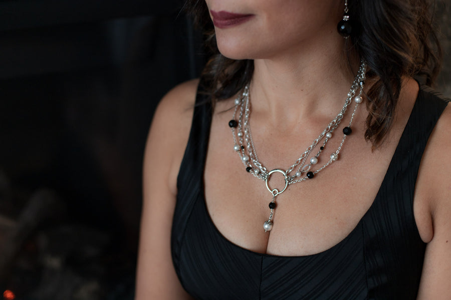 A woman in a black top wearing a Carolily Finery statement necklace made from sterling silver, onyx and European crystal pearls