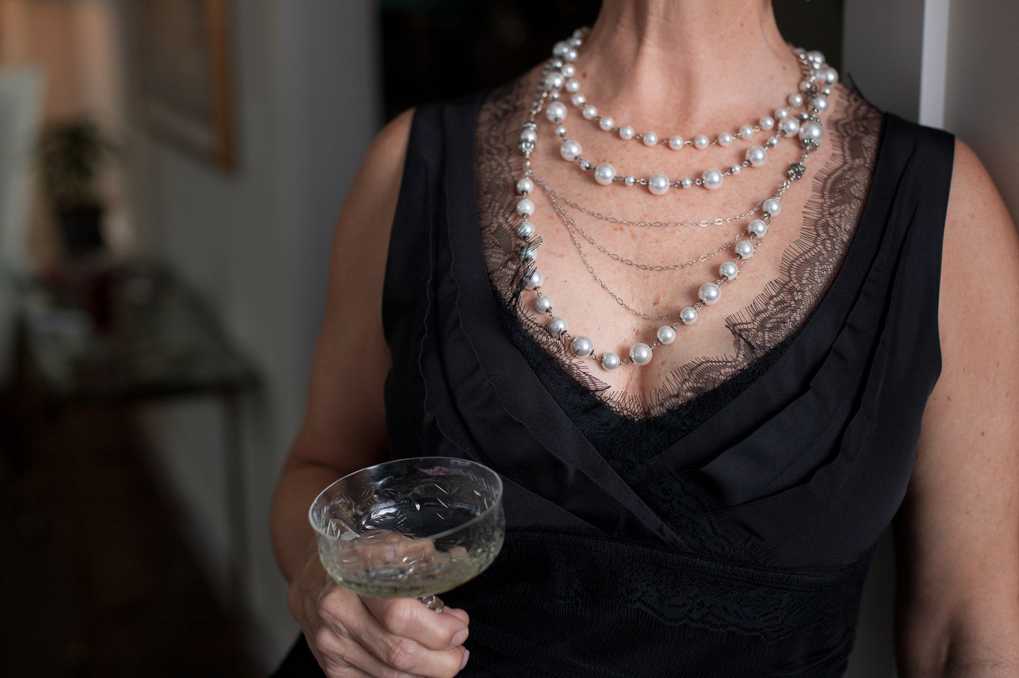 A woman wearing a Carolily Finery statement necklace made from European crystal pearls, sterling silver chains, silver plated chains