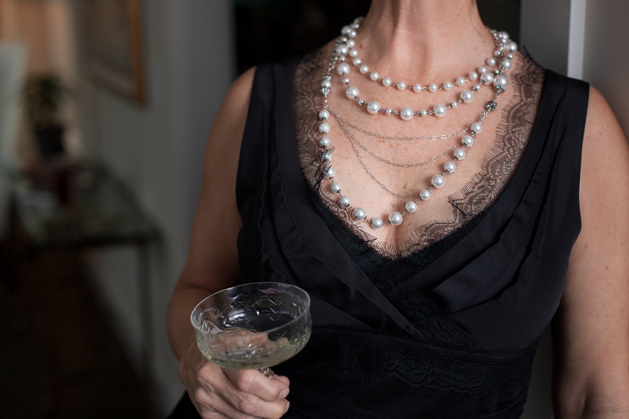A woman wearing a Carolily Finery statement necklace made from European crystal pearls, sterling silver chains, silver plated chains