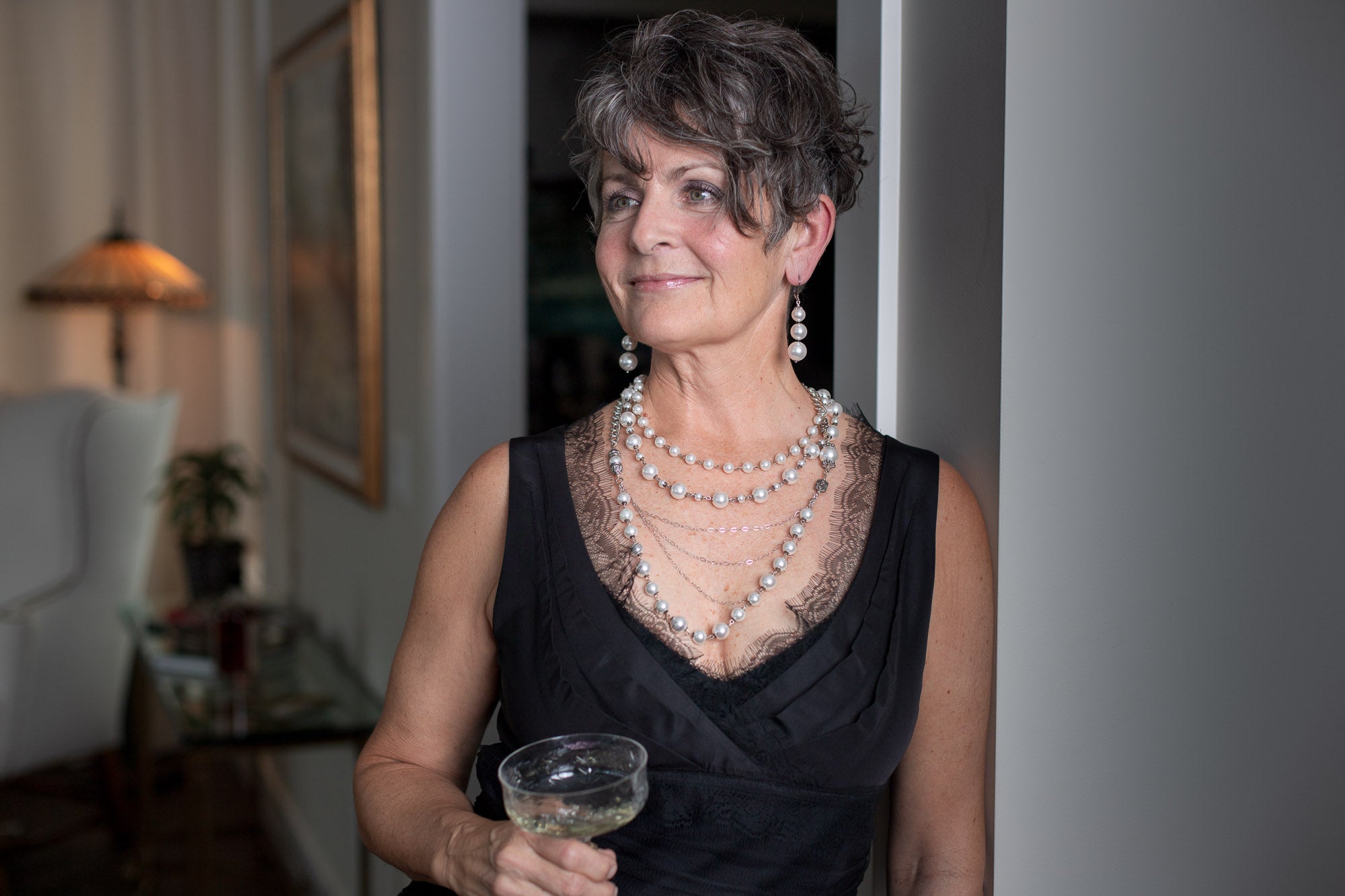 A woman smiling while wearing a Carolily Finery statement necklace made from European crystal pearls, sterling silver chains, silver plated chains