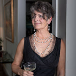 A woman smiling while wearing a Carolily Finery statement necklace made from European crystal pearls, sterling silver chains, silver plated chains