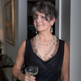 A woman smiling while wearing a Carolily Finery statement necklace made from European crystal pearls, sterling silver chains, silver plated chains