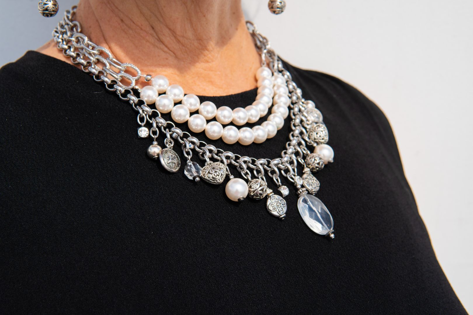 Silver, stainless steel and pearl charm necklace on woman's neck