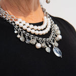 Silver, stainless steel and pearl charm necklace on woman's neck