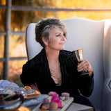 a woman in a black velvet blazer wearing a Carolily Statement necklace made of gold plated chain, various gemstones and freshwater pearls