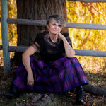 A woman sitting on the ground wearing a Carolily Finery necklace made from silver chain, black onyx, various gemstones and Swarovski crystal