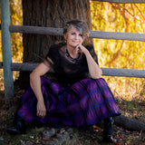 A woman sitting on the ground wearing a Carolily Finery necklace made from silver chain, black onyx, various gemstones and Swarovski crystal