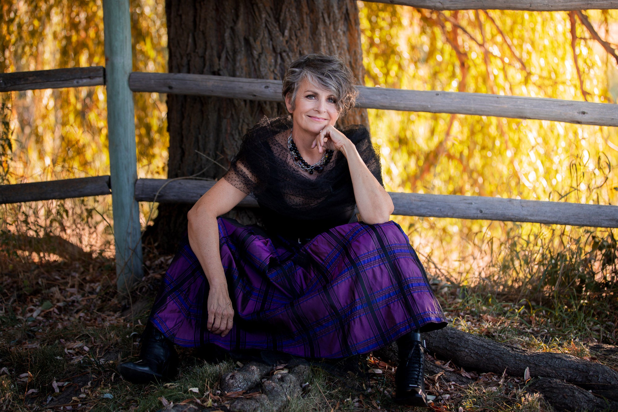 A woman sitting on the ground wearing a Carolily Finery necklace made from silver chain, black onyx, various gemstones and Swarovski crystal