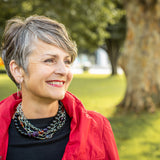 A woman in a red jacket wearing a Carolily Finery necklace made from silver chain, black onyx, various gemstones and Swarovski crystal