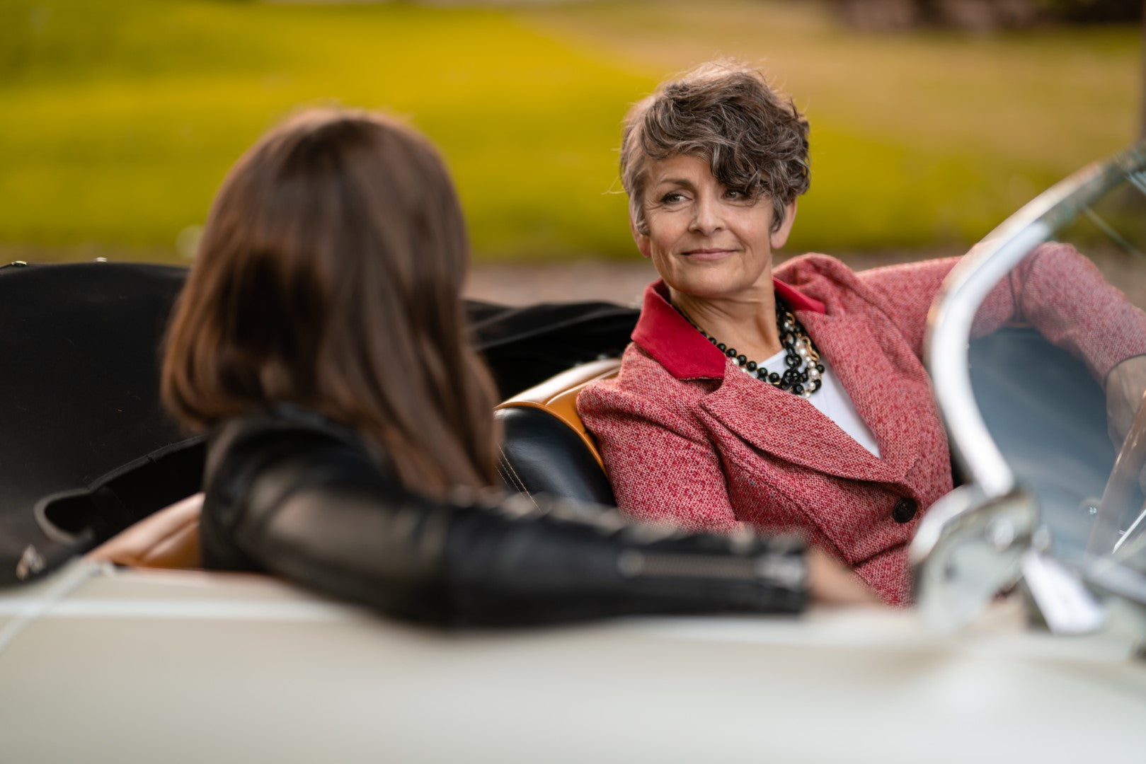 A woman in a car wearing a Carolily Finery statement necklace made from onyx, Swaorvski crystal, gold plated chains and pearls