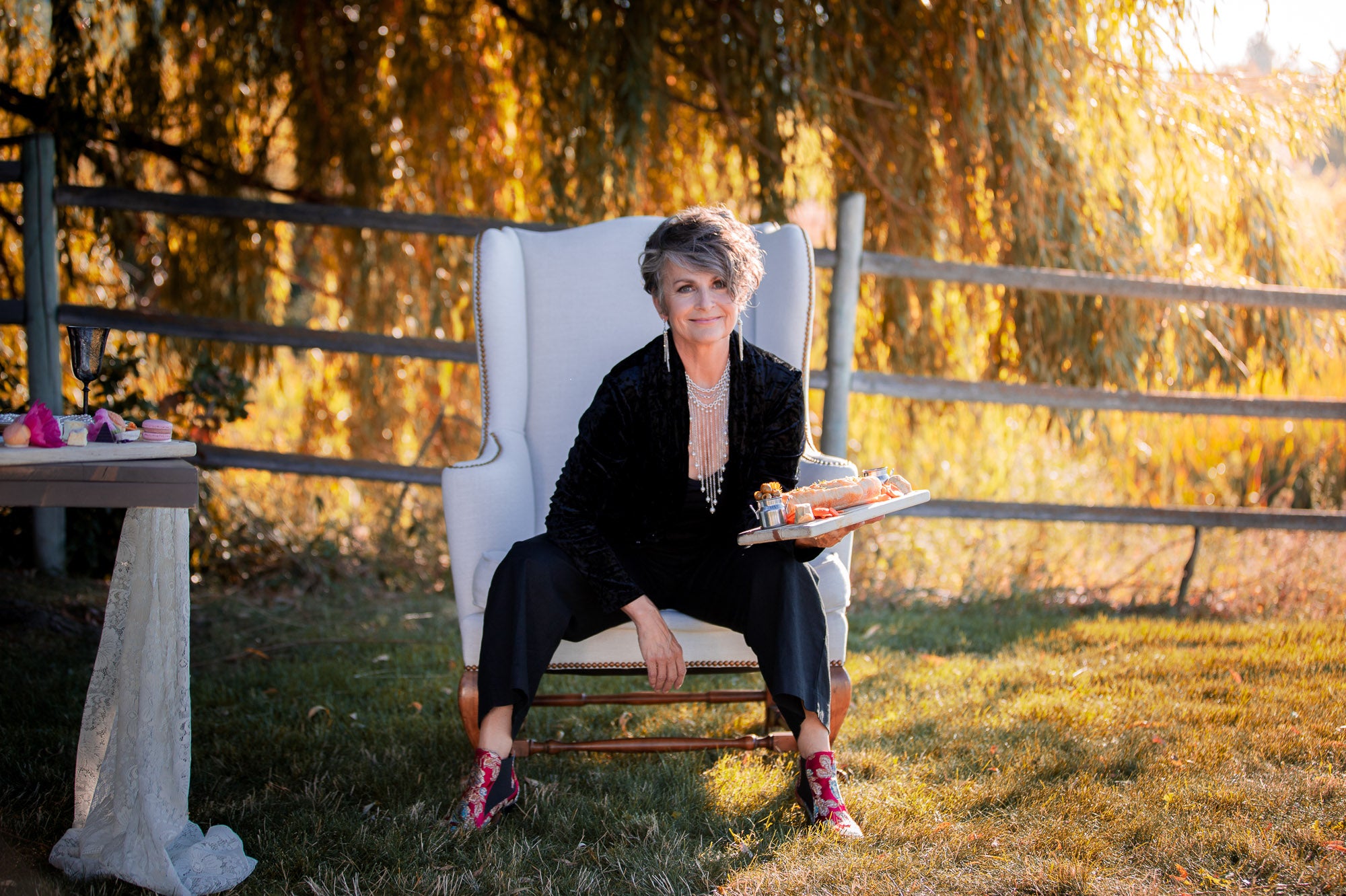 A woman in an armchair wearing a Carolily Finery statement necklace made from silver plated chain and European crystal pearls