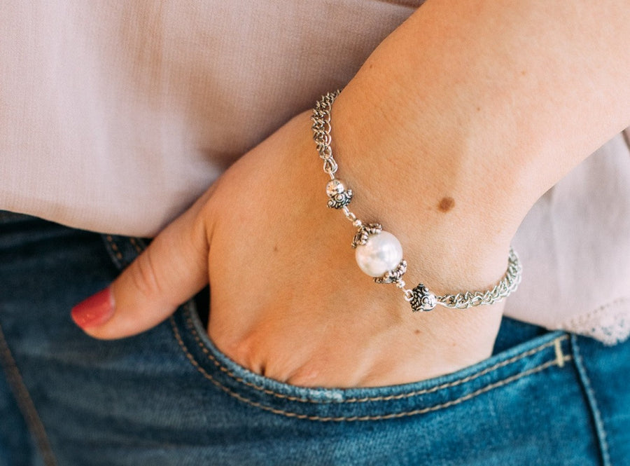 a woman's wrist wearing a Carolily Finery bracelet made from European pearl, sterling silver beads, silver accents, antiqued silver chains