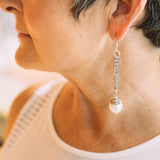 A woman wearing Carolily Finery earrings made from European pearl, sterling silver accents, stainless steel chains and earwires