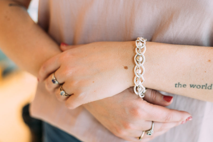 A woman's wrist wearing a Carolily Finery bracelet made from sterling and silver plated chain, European crystal pearls and sterling encased cubic zirconia accent
